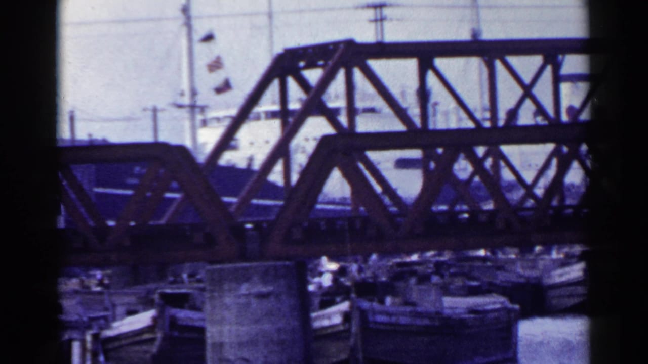 Steel truss bridge over water with small boats below and dark 8mm frame edges.