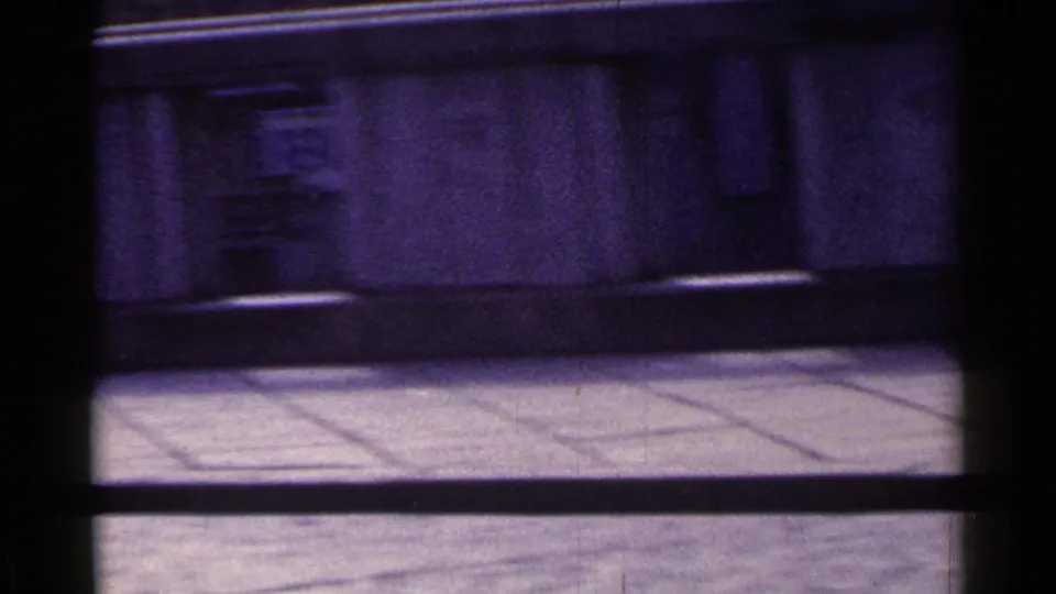 1953 Japan street frame with a blurred car moving past the concrete building frontage and sidewalk.