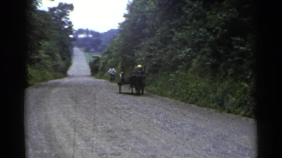 1953 Japan frame with a horse-drawn cart at the right edge of a rural road and a cyclist ahead in the distance.