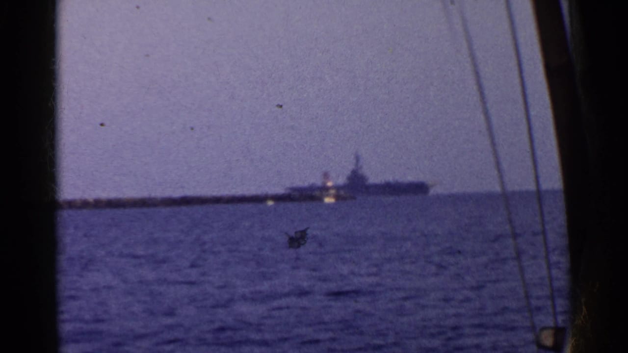 Distant large naval vessel on the ocean with dark frame edges and vertical lines in front.