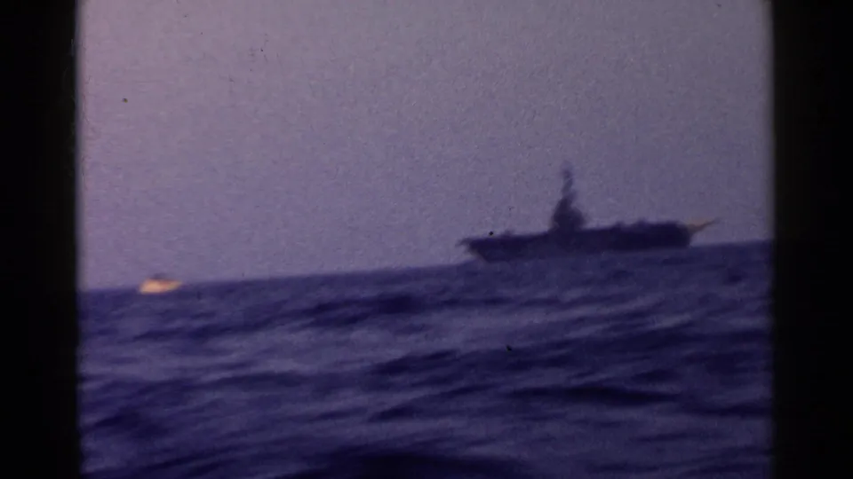 1955 California 8mm frame showing a distant ship beyond choppy ocean water, with dark film-frame edges visible.