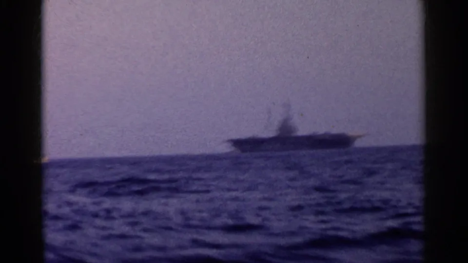 Blue-tinted 8mm view of a larger vessel on the horizon across rough ocean water, likely filmed from another boat.
