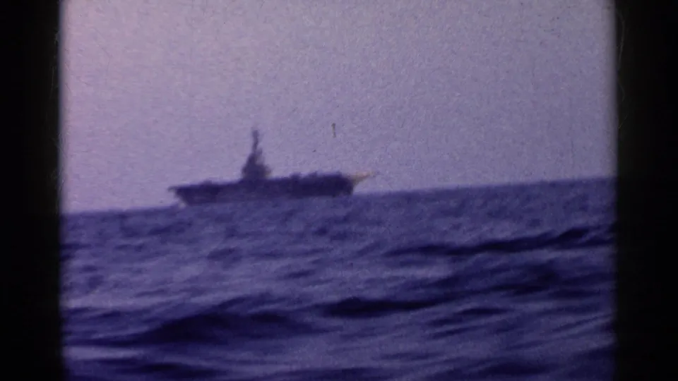 1955 California home-movie frame with a distant boat silhouetted against hazy sky and choppy sea.