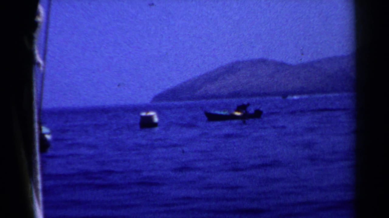Small boats on blue ocean water with hazy mountains in the distance.