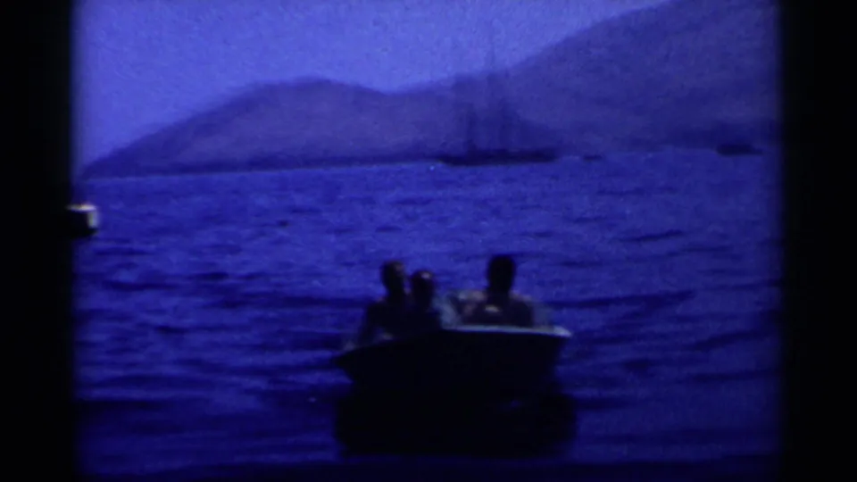 Three men ride in a small motorboat on California coastal water, with mountains and boats behind them.