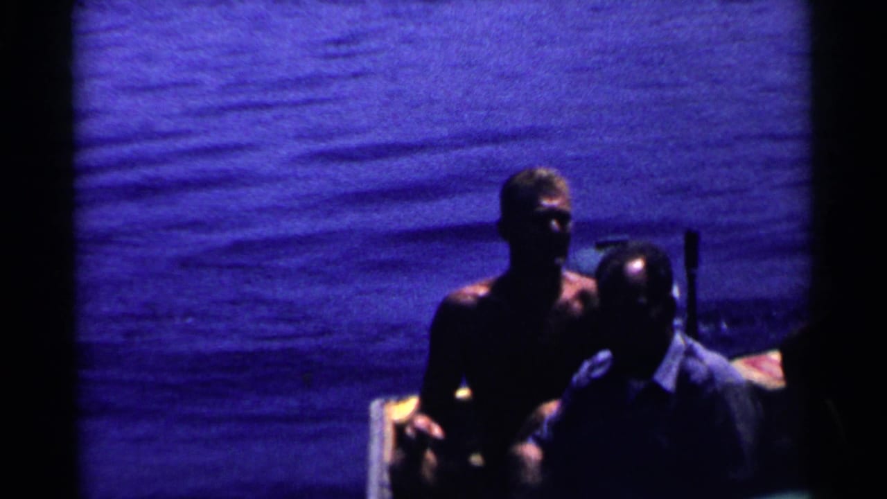 Two adult men are seen close to a small boat on open water.