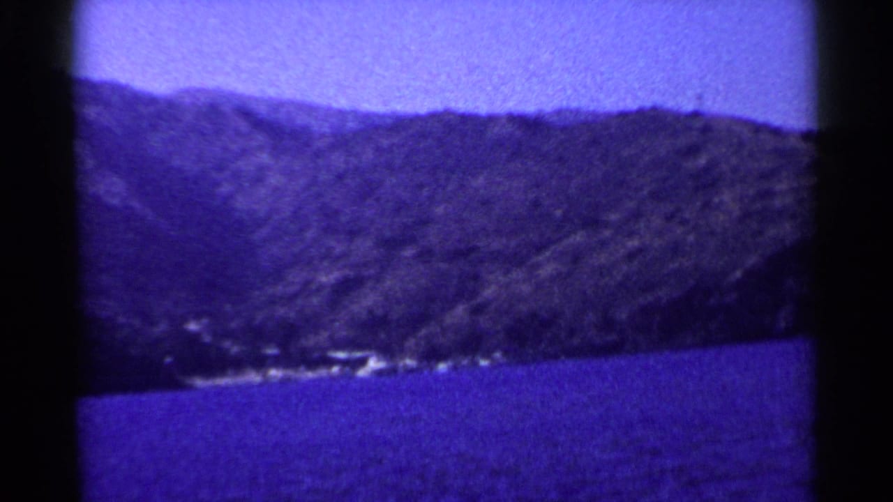 Distant hillside above blue lake water with a small shoreline settlement visible.