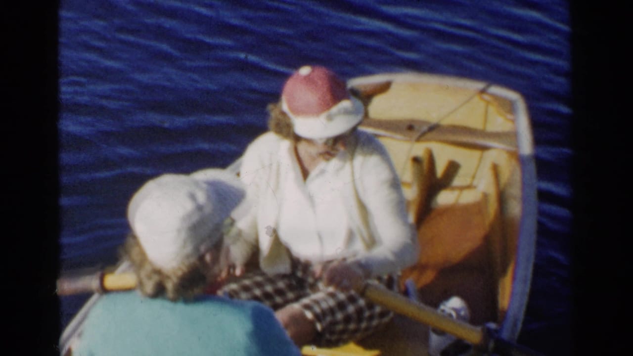 In 1955 California home-movie footage, two women sit in a small dinghy while the woman in a sun hat handles an oar.