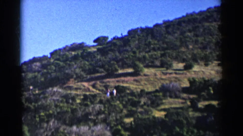 Wide 8mm view of a California hillside with paths, brush, blue sky, and two distant people in the landscape.