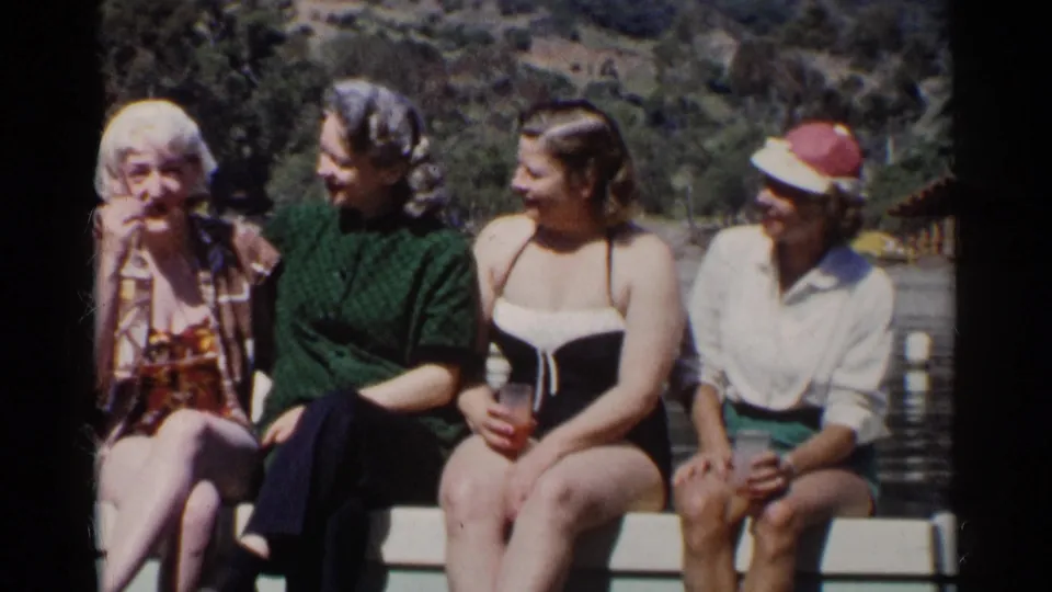 In a California lake home movie, three women turn toward an older woman seated at the end of the railing.