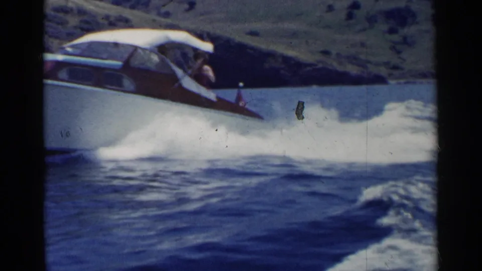 The 8mm frame shows the motorboat in motion on a California lake, with spray and rolling water filling the foreground.