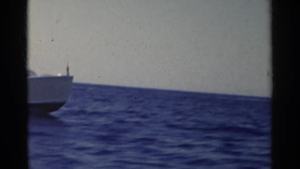 8mm frame from the California coast showing open water, a partial boat edge, and a pale sky near the horizon.