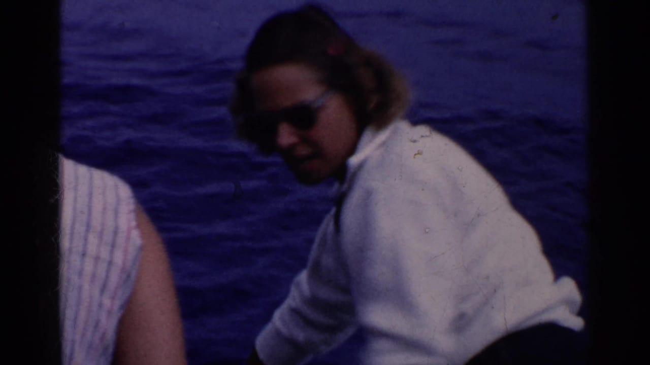 Two adults seated on a boat with blue ocean water behind them.