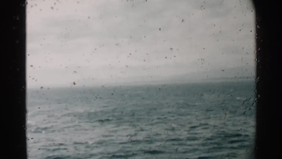 1958 Hawaii home-movie frame showing calm ocean water, a faint horizon line, and film specks from the scanned 8mm source.