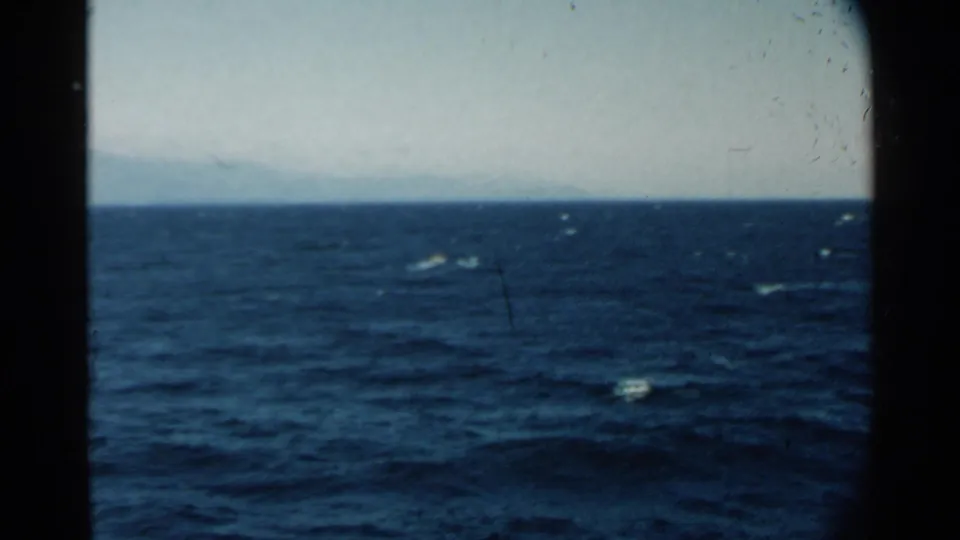 1958 8mm view of blue open water near Pearl Harbor, with whitecaps and a faint landform on the horizon.