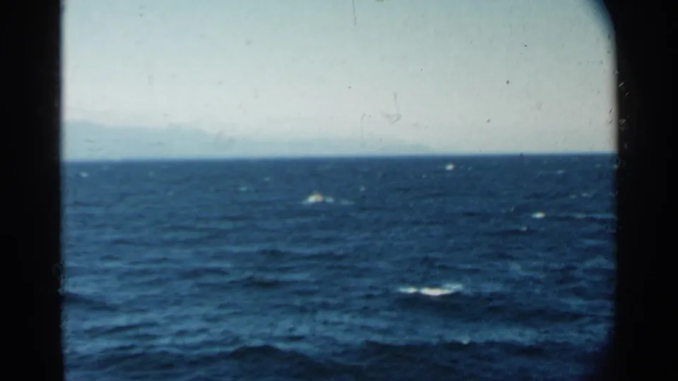 Open ocean near Pearl Harbor in 1958, seen from a vessel with blue water, whitecaps, and archival film wear.