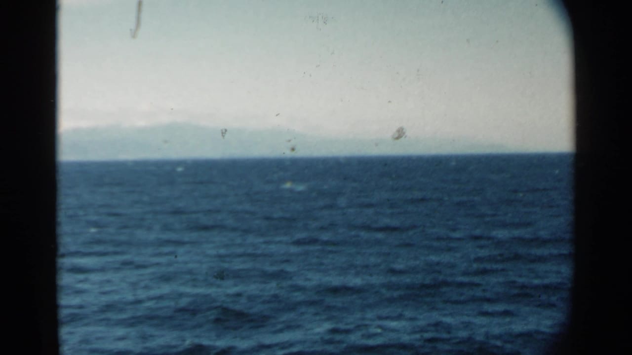 Blue ocean and distant land seen through dark film frame borders.