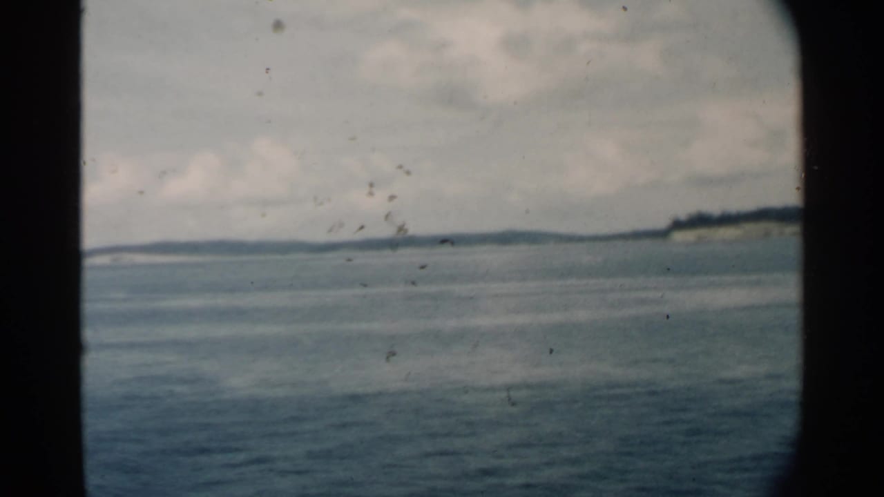 Distant island horizon over calm water, divided by dark vertical window framing.