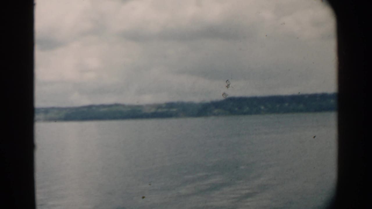 Calm water and distant shoreline seen through dark frame edges under cloudy sky.
