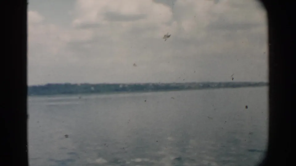 Pearl Harbor water and low distant land appear through a dark framed opening in this 1958 8mm travel shot.