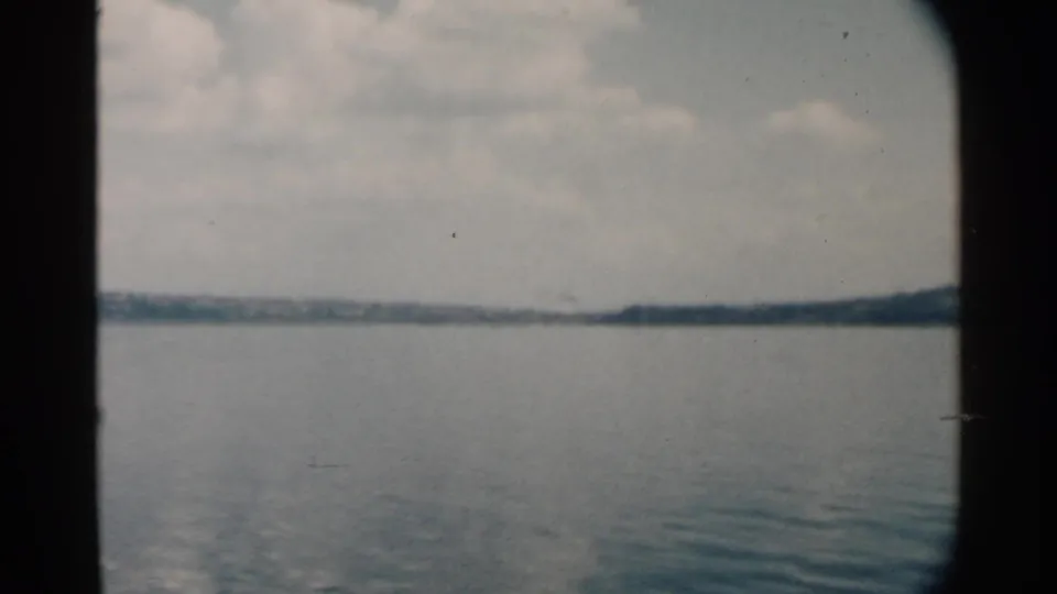 The final frame shows calm Pearl Harbor water and a low shoreline under clouds, with 8mm grain and dark window framing.