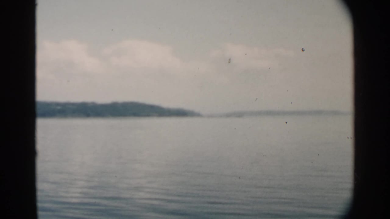 Calm water and distant shoreline seen through a dark divided frame.