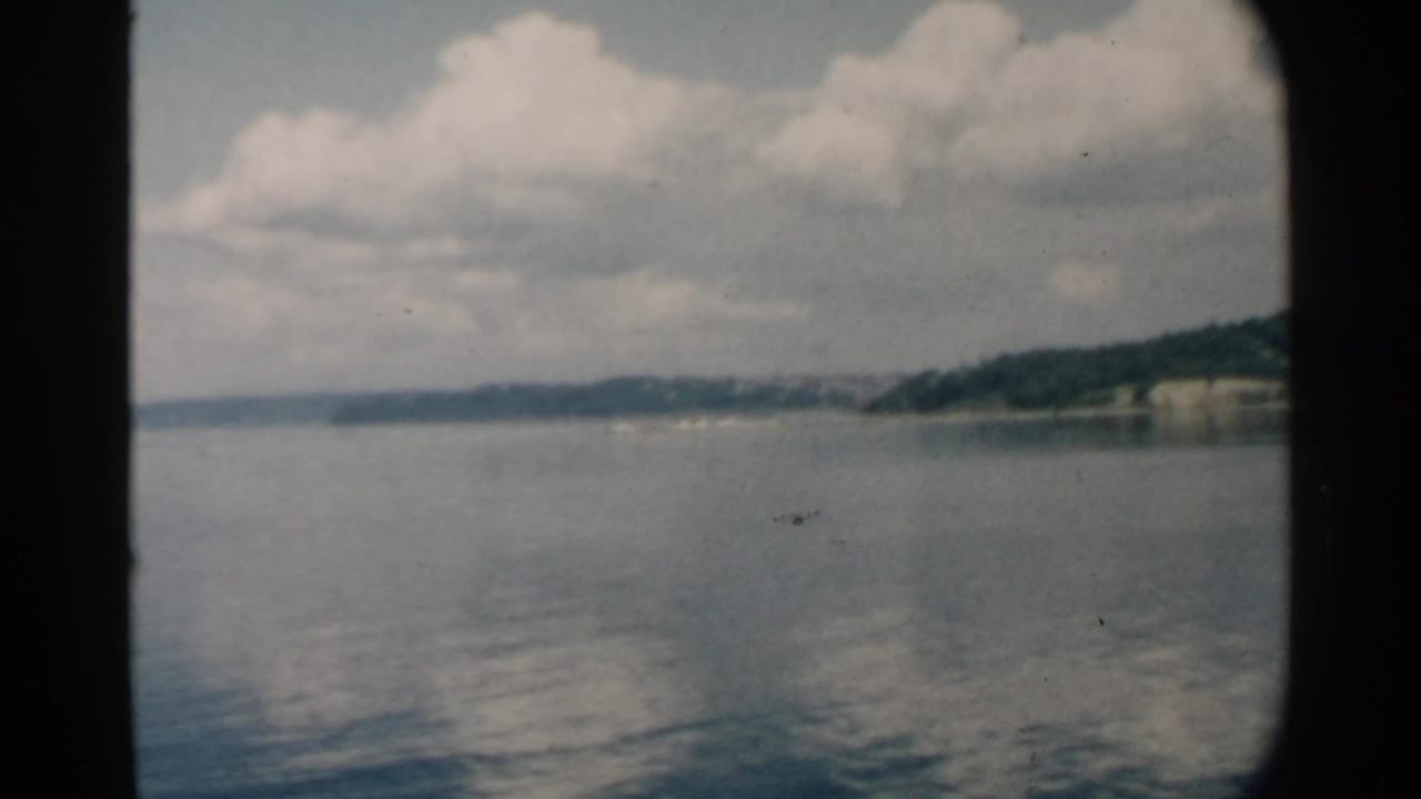Low green shoreline and clouds across calm harbor water.