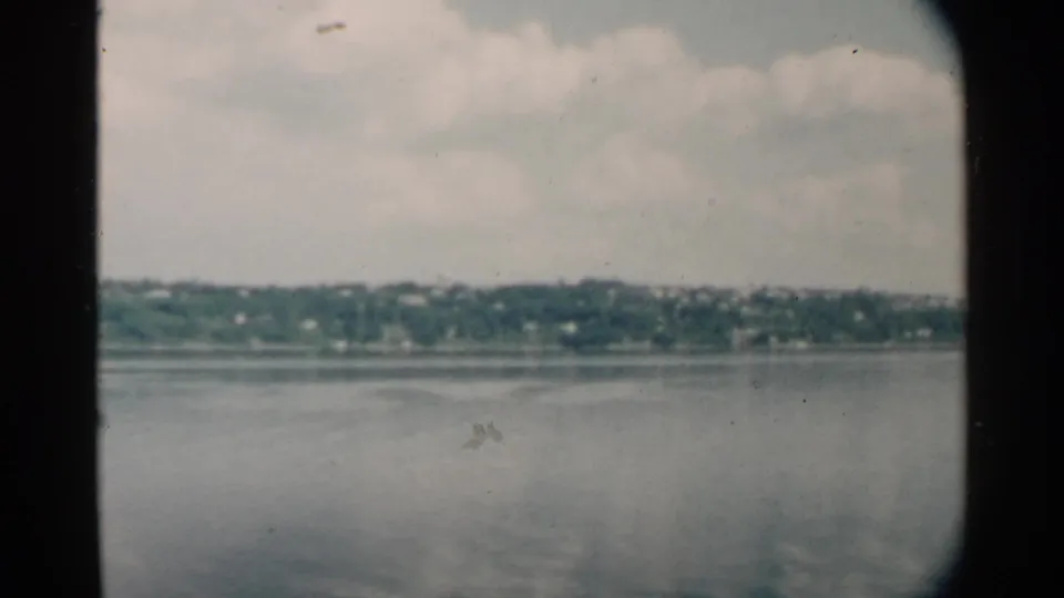 Wide 1958 Pearl Harbor view across still water toward a distant green shoreline, with no people visible.