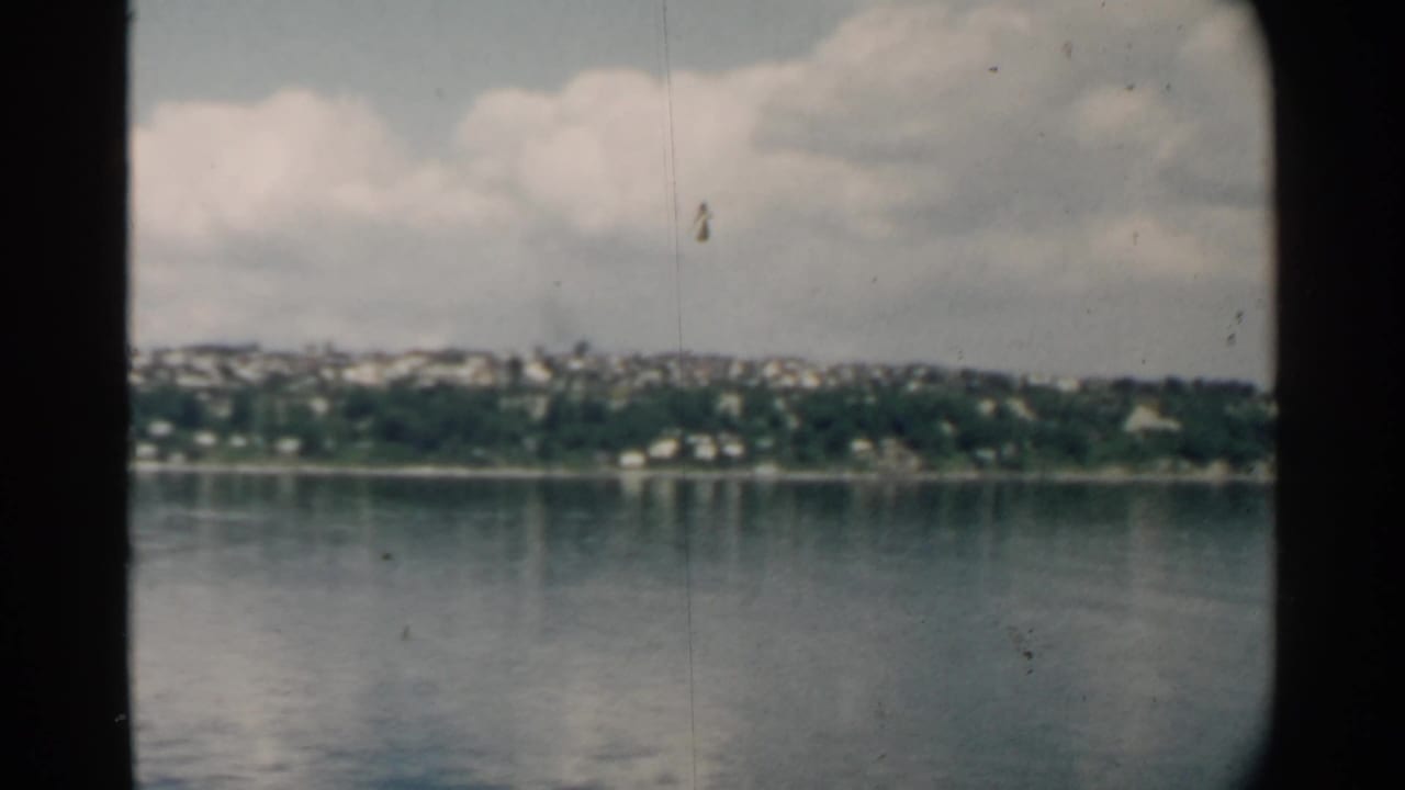 Distant shoreline across calm harbor water under a cloudy sky.