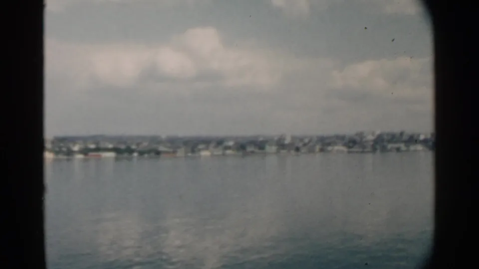 1958 8mm view across Pearl Harbor toward a distant residential waterfront, with soft focus and muted color.
