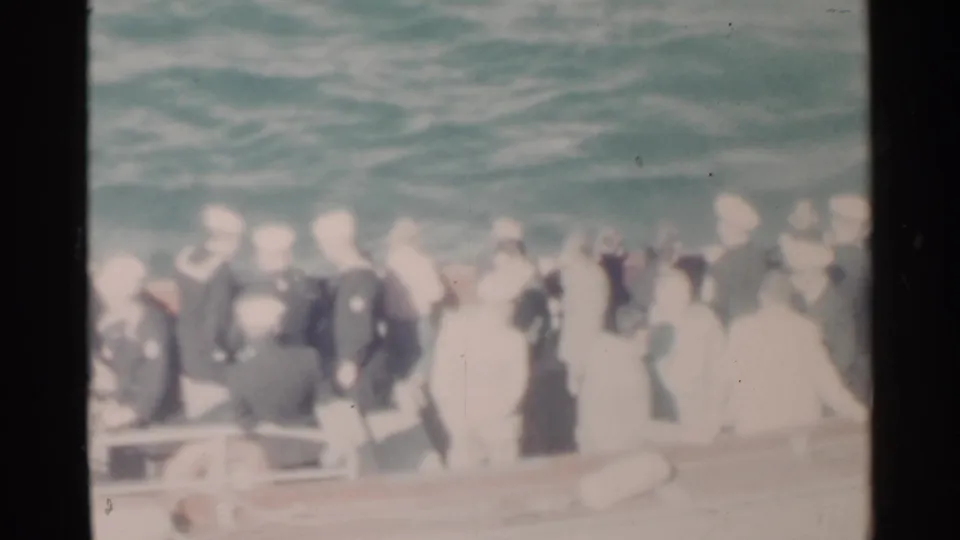 Pearl Harbor 1958 home-movie frame with uniformed Navy personnel crowded along the rail of a small boat.