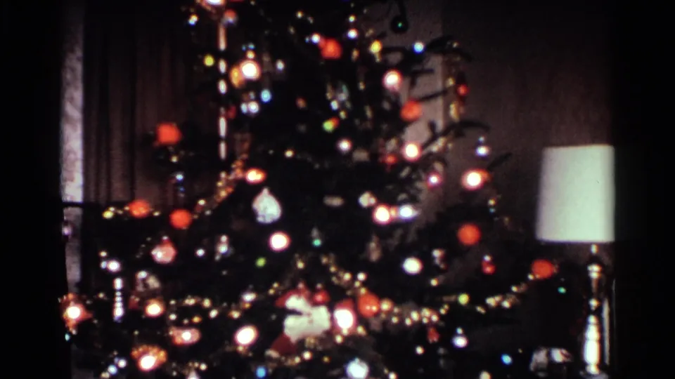1959 Ohio holiday interior showing an illuminated Christmas tree with ornaments and tinsel beside a table lamp.