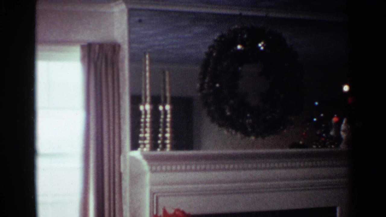 1959 Ohio home interior showing a decorated fireplace mantel with wreath, candlesticks, curtains, and a partially visible Christmas tree.