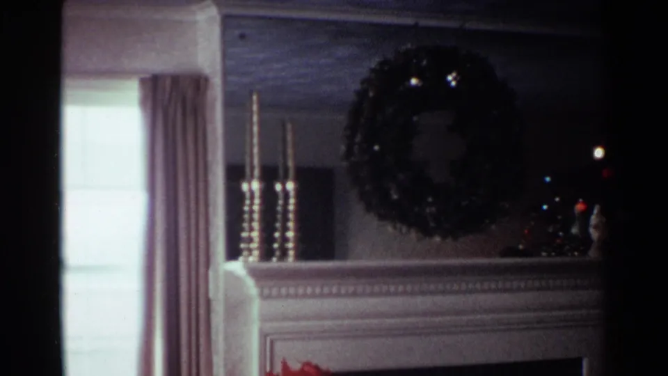 1959 Ohio home interior showing a decorated fireplace mantel with wreath, candlesticks, curtains, and a partially visible Christmas tree.