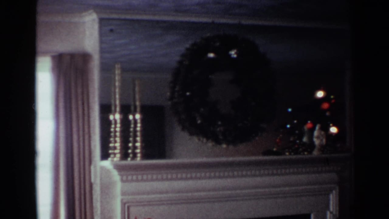 1959 Ohio living room detail with a wreath over the mantel, tall candlesticks, drapery, and colored Christmas lights at right.