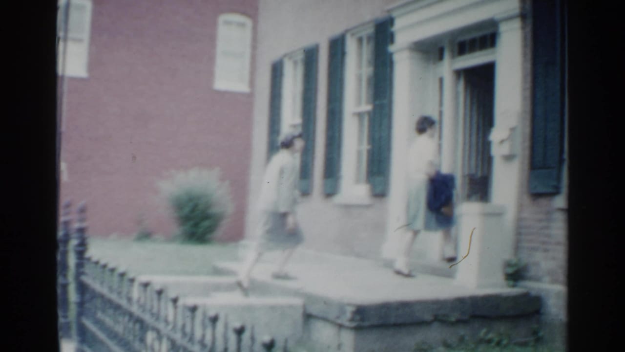 Two women walking near the entrance of a brick residential building.