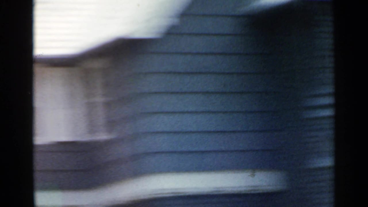 Blurred moving view of a blue-sided residential exterior with a bay window.