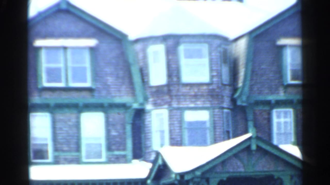 1959 San Francisco frame of a multi-story brick residential facade with green trim, bay windows, and a small roofed entry.