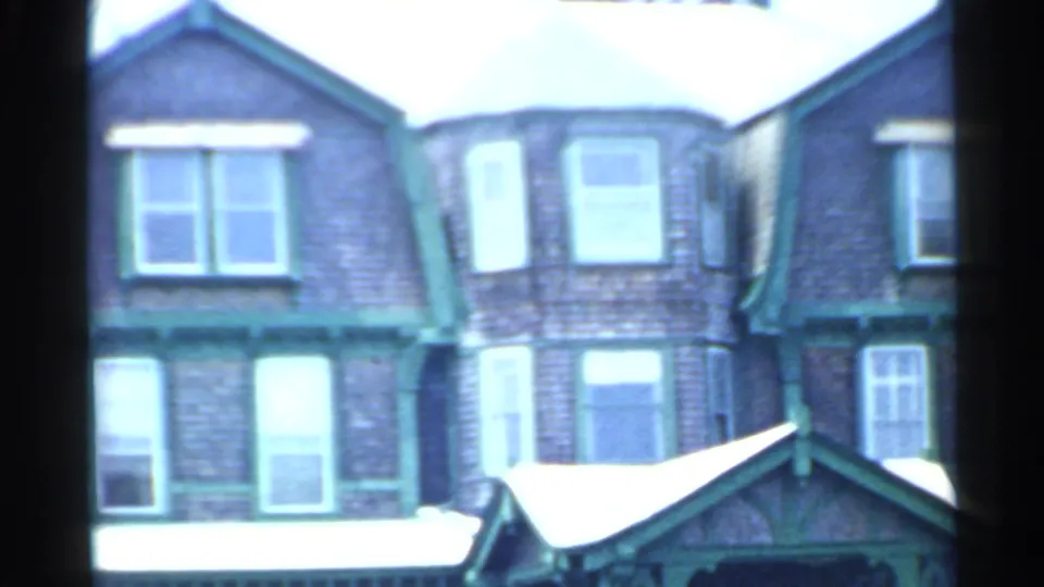 1959 San Francisco frame of a multi-story brick residential facade with green trim, bay windows, and a small roofed entry.