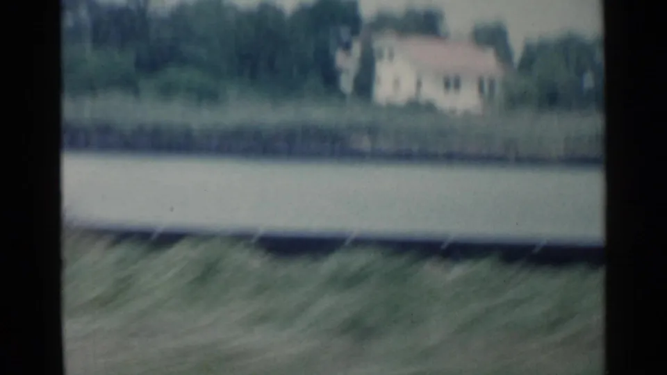 Brief 1959 San Francisco 8mm view across a waterway toward trees and a distant light-colored house.