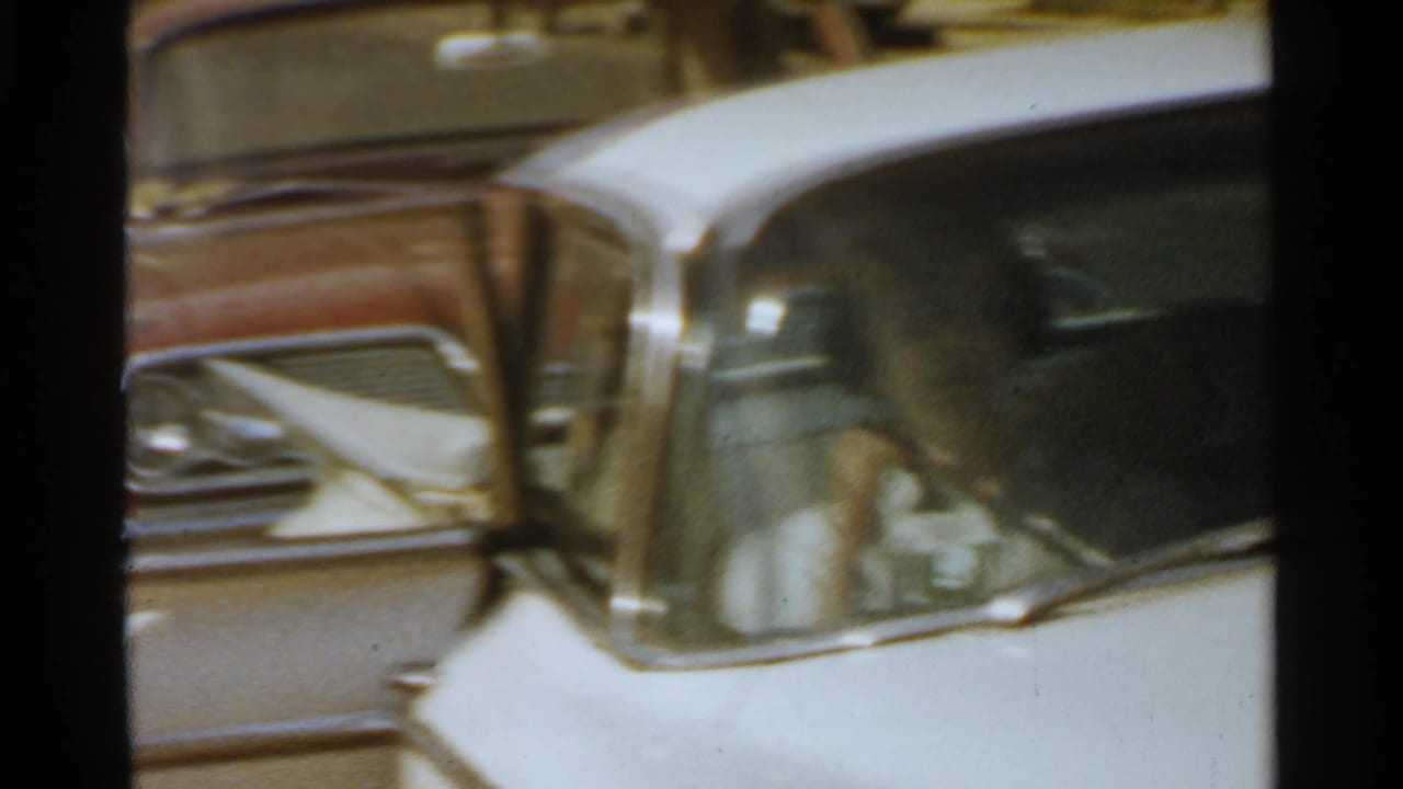 White vintage car with chrome trim parked beside a residential street.