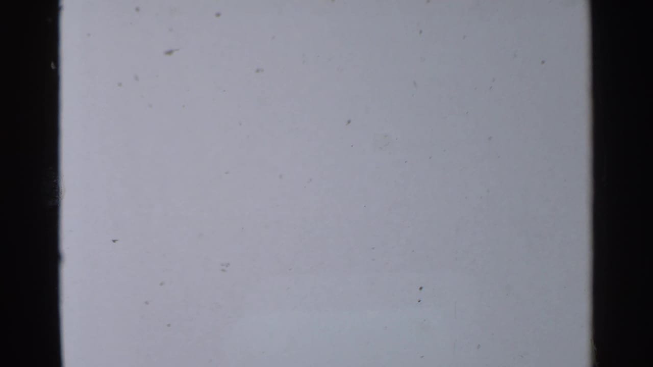 1959 8mm frame with a mostly blank pale field, scattered dust, slight grain, and dark film edges.