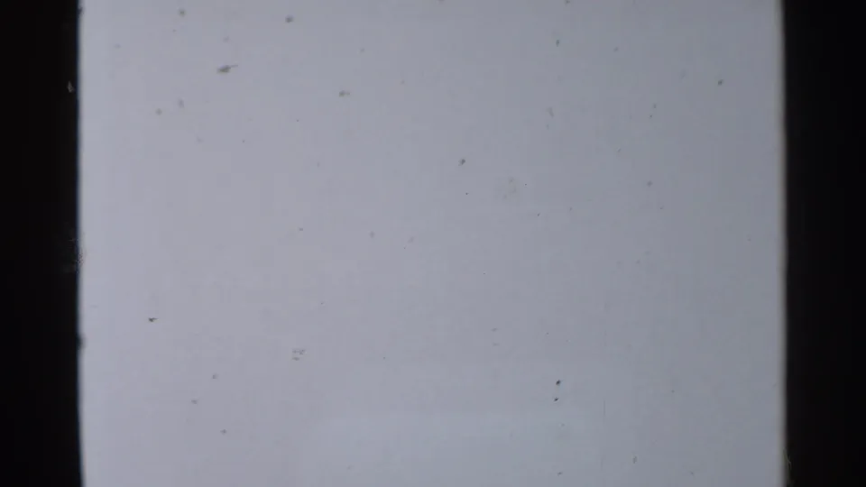 1959 8mm frame with a mostly blank pale field, scattered dust, slight grain, and dark film edges.