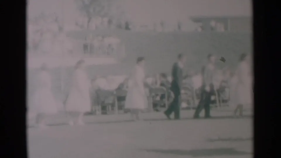 1959 South Dakota 8mm frame showing the end of a brief outdoor procession beside tables and seated people.