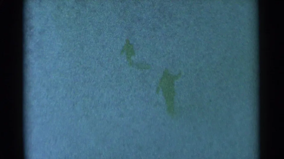 Two distant bundled figures appear against a snow-covered South Dakota landscape in 1959 home-movie footage.