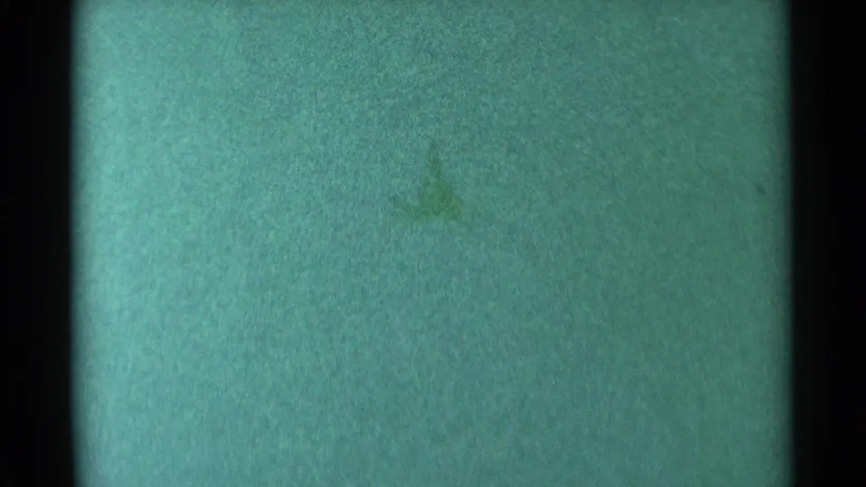 1959 South Dakota 8mm frame showing green-blue tint, dark film edges, grain, dust, and an obscuring horizontal band.