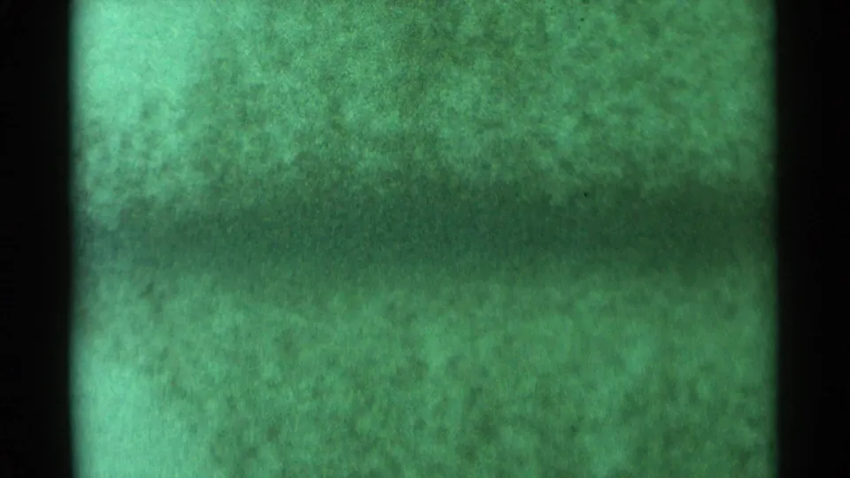 Obscured 1959 South Dakota 8mm storm frame with green tint, mottled grain, and a dark central film edge or obstruction.