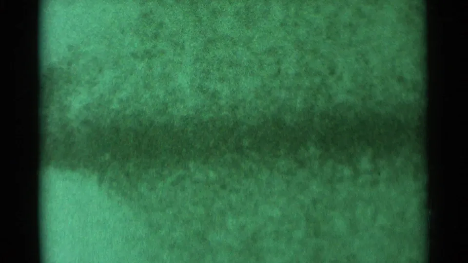 1959 South Dakota 8mm frame showing a green-white whiteout effect, dark film borders, and heavy grain without identifiable people.