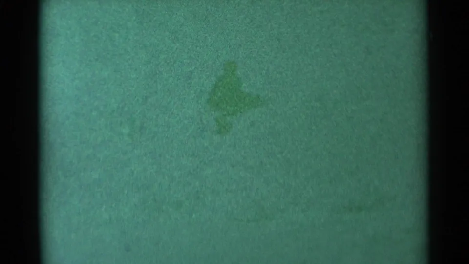 1959 South Dakota 8mm frame with mostly blank green film, dark gate edge, faint stain patches, dust, and analog grain texture.