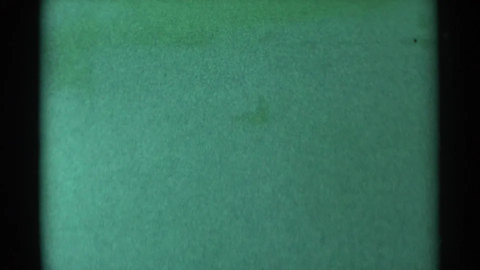 A green-tinted 8mm frame from the South Dakota 1959 source, showing film grain, dark borders and no identifiable person or sled.